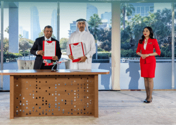 Tony Fernandes and Bahraini officials seated at formal ceremony table during agreement signing in Manama, Bahrain, with branding banners and documents visible